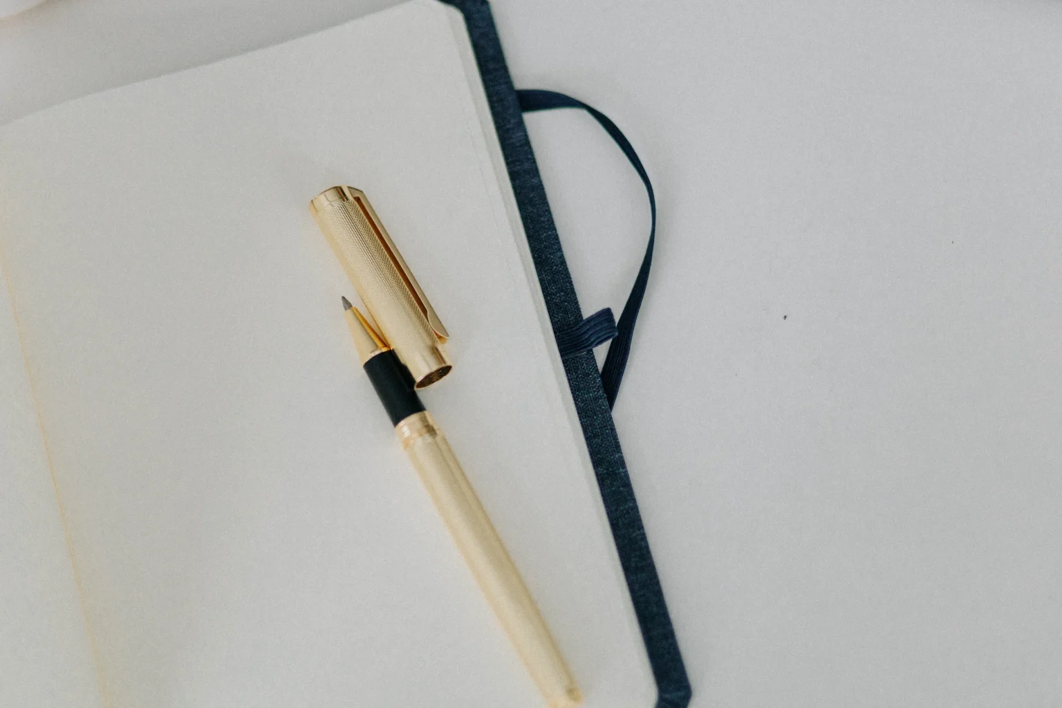 Nahaufnahme: goldener Stift auf einer leeren Notizbuchseite
