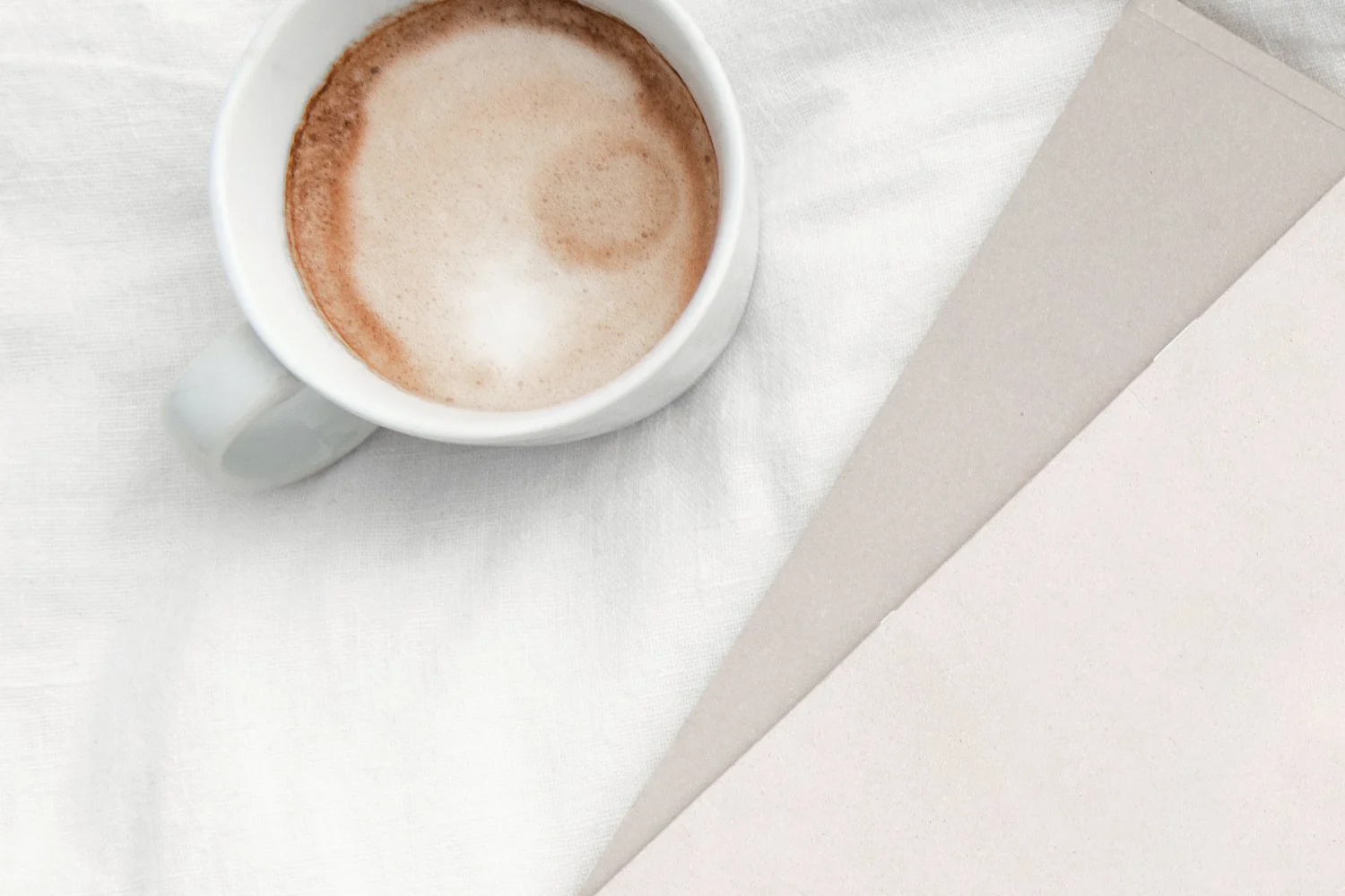 Tasse Kaffee und Papier auf heller Leinendecke