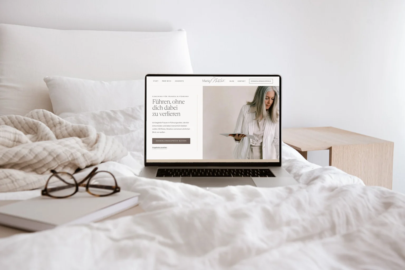 Laptop mit der Essential Website Vorlage Linen auf einem hellen Bett