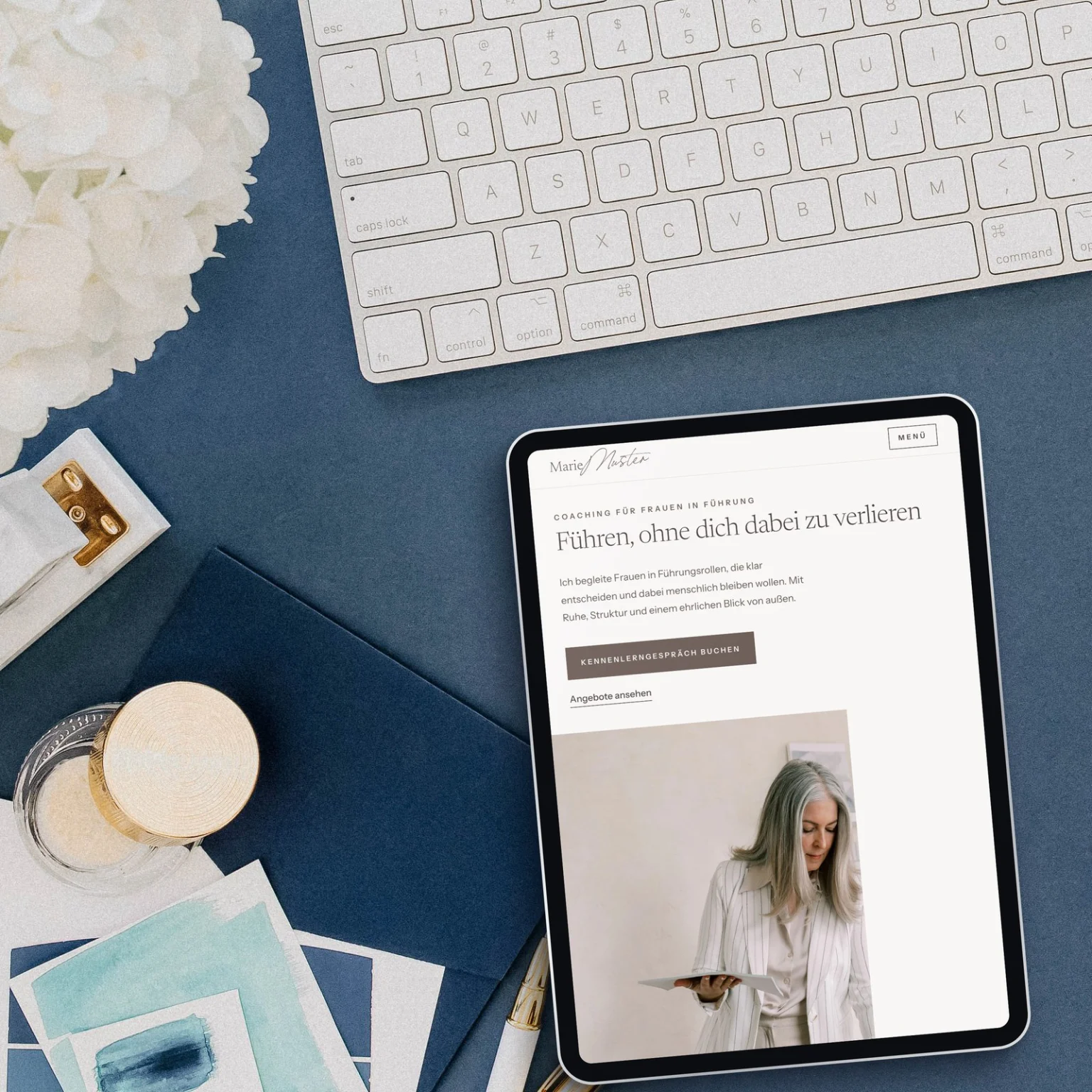 Tablet mit der Essential Website Vorlage Linen auf einem navyblauen Schreibtisch mit Tastatur und Hortensien