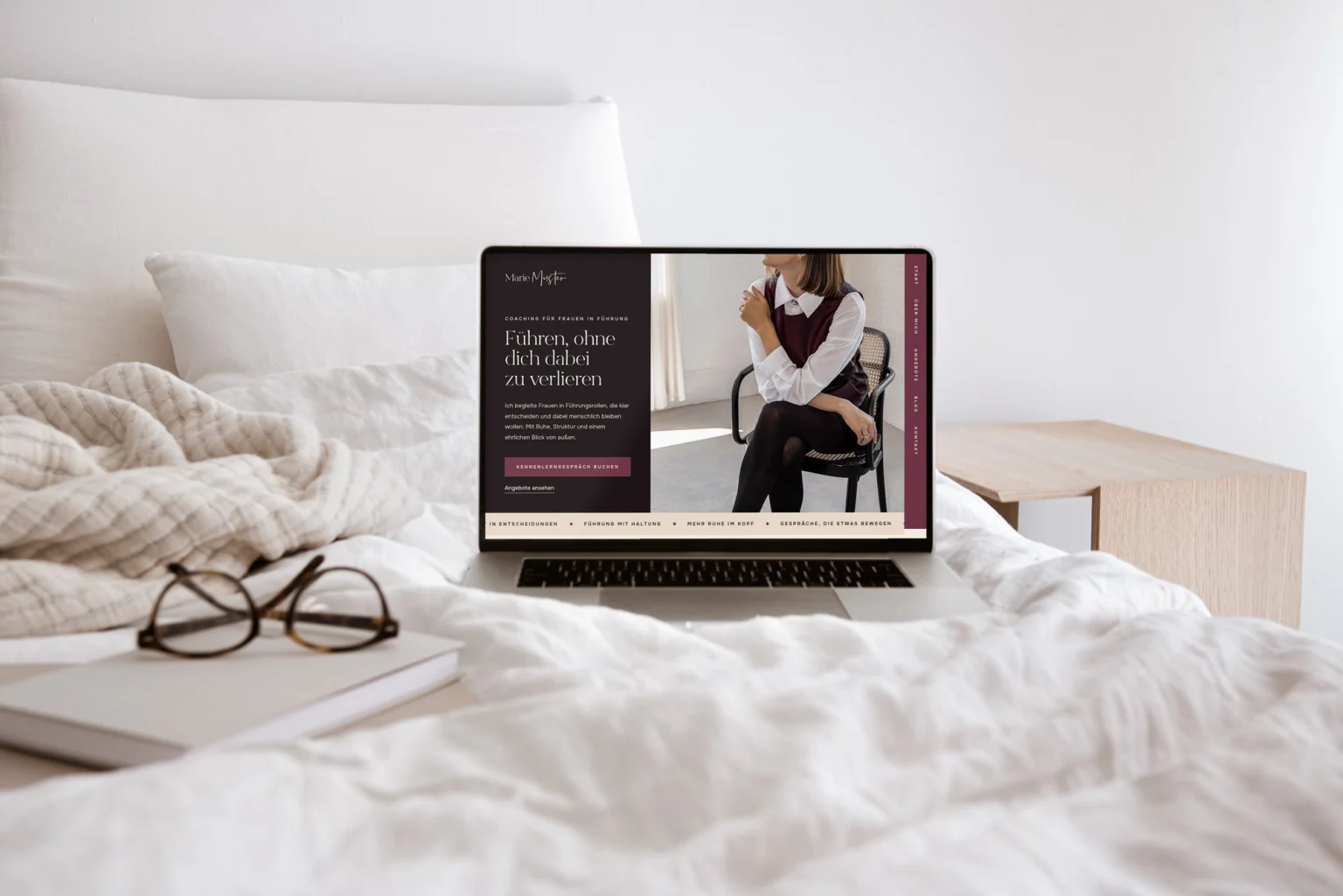 Laptop mit der Essential Website Vorlage Velvet auf einem hellen Bett